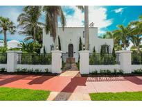 Charming two-story home with a black metal fence and a beautiful array of mature palm trees at 76 S Washington Dr, Sarasota, FL 34236