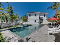 An inviting backyard pool and patio area is adjacent to a pristine white home with a red tile roof at 803 Gladiolus St, Anna Maria, FL 34216