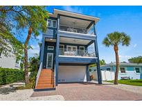 Stunning three-story home featuring dual balconies and a brick-paved driveway at 159 Crescent Dr, Anna Maria, FL 34216