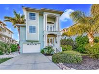 Charming two-story coastal home with a light blue exterior, lush landscaping, and a two-car garage at 426 Magnolia Ave, Anna Maria, FL 34216