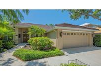 Charming single-story home with a tile roof, lush landscaping, and a two-car garage in a tropical setting at 5355 Anthony Ln, Sarasota, FL 34233