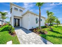 Modern home exterior featuring a paved walkway, manicured lawn, and lush tropical landscaping at 5939 Redbay Blvd, Bradenton, FL 34210