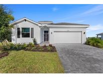 Charming single-story home with a manicured lawn, a gray driveway and a two-car garage under a clear sky at 8134 Shore Lake Dr, Englewood, FL 34224
