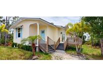 Charming home with pale yellow siding, a baby blue front door, and a raised deck with steps leading down to the yard at 8297 Strasse Blvd, Punta Gorda, FL 33982