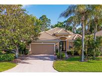 Charming single-story home with a tile roof, lush landscaping, and a brick driveway at 9120 Willow Brook Dr, Sarasota, FL 34238