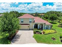 Charming two-story home with a well-manicured lawn, and a paver driveway leading to a two-car garage at 12838 Daisy Pl, Bradenton, FL 34212
