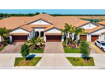 Stunning home exterior with a tile roof, multiple garages, a well-manicured lawn, and lush landscaping at 17576 Holly Well Ave, Wimauma, FL 33598