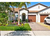 Charming single-Gathering home features a manicured lawn and beautiful landscaping with colorful flowers and palm trees at 17578 Holly Well Ave, Wimauma, FL 33598