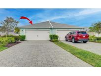 Charming villa with a gray brick driveway, a two-car garage, and beautiful landscaping at 17732 Wayside Bnd, Punta Gorda, FL 33982