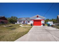 Charming single-story home featuring a red garage door and accent trim, set against a clear blue sky at 1821 16Th E Ave, Bradenton, FL 34208