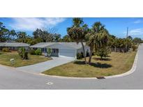 Charming single-story home boasts a well-manicured lawn, palm trees, and a paved driveway at 2647 Britannia Rd, Sarasota, FL 34231