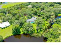 Expansive aerial view of wooded acreage, lake frontage, pool and mature trees define this private estate at 4576 Cooper Rd, Sarasota, FL 34232