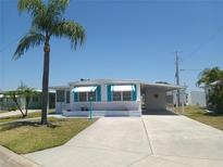 Charming home featuring a carport, blue awnings, a palm tree and a spacious driveway at 4920 Boca Raton Ave, Sarasota, FL 34234