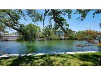 Beautiful waterfront view with lush trees and a glimpse of the home, offering a serene and picturesque setting at 5033 Oxford Dr, Sarasota, FL 34242