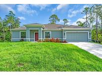 Charming single-story home with a well-manicured lawn, colorful flowers, and an attached two-car garage at 5672 Jonesboro Ave, North Port, FL 34288