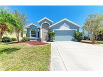 Charming home featuring a well manicured lawn with a colorful array of flowers and mature trees at 6106 New Paris Way, Ellenton, FL 34222