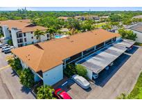 A bright exterior daytime shot of a multi-unit dwelling with covered parking, pool, and tropical landscaping at 7201 Curtiss Ave # 2D, Sarasota, FL 34231