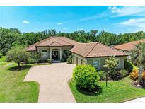 Charming home with a tile roof, lush landscaping, and a paved driveway at 9734 Carnoustie Pl, Bradenton, FL 34211