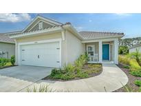 Beautiful home featuring a two-car garage, elegant landscaping, and a charming front porch with rocking chairs at 10105 Canaveral Cir, Sarasota, FL 34241