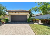 Home exterior features a two-car garage, manicured landscaping and a brick-paved driveway in a well-maintained community at 10205 Saint Francis Ter, Palmetto, FL 34221