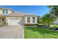 Charming home featuring manicured lawn, brick driveway, two-car garage and colorful flowers around the foundation at 11847 Meadowgate Pl, Lakewood Ranch, FL 34211