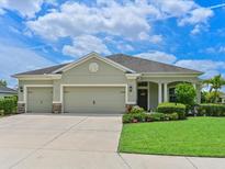 Charming single-story home showcasing a well-manicured lawn and a three-car garage with beautiful landscaping at 16711 Rivers Reach Blvd, Parrish, FL 34219