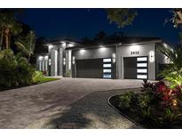 Stunning modern home with a two-car garage, lush landscaping, and elegant exterior lighting at night at 2632 Hawthorne St, Sarasota, FL 34239
