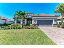 Beautiful single-story home with a manicured lawn, colorful flowerbeds, and a paver driveway at 4908 Tivoli Run, Bradenton, FL 34211
