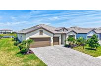 Beautifully landscaped home with a three-car garage and a paved driveway under a sunny blue sky at 4975 Seafoam Trl, Bradenton, FL 34211