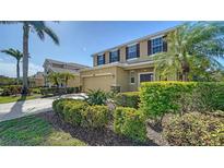 Two-story home with a tan exterior, dark shutters, well-manicured landscaping, and a two-car garage at 5403 Mang Pl, Sarasota, FL 34238