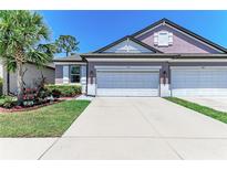 Charming home featuring a well-manicured lawn, light purple walls, and a spacious two-car garage at 5957 Amberly Dr, Bradenton, FL 34208