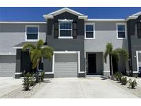 Charming two-story townhome featuring a one-car garage, dark shutters, and well-manicured landscaping at 8864 Milestone Dr, Sarasota, FL 34238