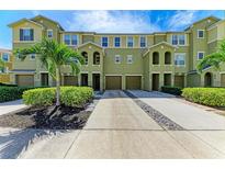 Charming green townhouse exterior featuring well-manicured landscaping, individual driveways, and lush palm trees at 8943 White Sage Loop, Lakewood Ranch, FL 34202