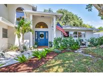 Charming home featuring a blue front door, decorative wreath, manicured landscaping, and an American flag at 2111 Ivory Pl, Sarasota, FL 34239