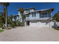 Beautiful exterior of home featuring a multi-car garage, balconies, landscaping, and palm trees at 222 Willow Ave, Anna Maria, FL 34216