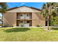 Two-story building with balconies overlooking a green lawn and mature palm trees offering curb appeal at 2950 Clark Rd # 113, Sarasota, FL 34231