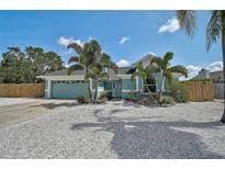 Charming turquoise home featuring a well-manicured lawn with tropical landscaping and a two-car garage at 6924 34Th W Ave, Bradenton, FL 34209