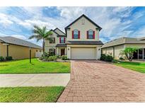 Charming two-story home with brick driveway, well-manicured lawn, and vibrant landscaping at 2084 La Palma Ave, Port Charlotte, FL 33953