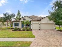 Charming single-story home featuring a manicured lawn, a three-car garage, and tropical landscaping at 2254 50Th Street E Cir, Palmetto, FL 34221