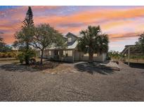 Charming home with a gravel driveway and beautiful landscaping at sunset at 28706 102Nd E Dr, Myakka City, FL 34251