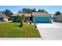 Charming teal home features a lush green lawn, palm tree, and matching teal garage door at 4219 Berkshire Dr, Sarasota, FL 34241