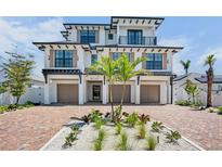 Stunning three-story home with a brick driveway, three car garage, and lush tropical landscaping at 723 S Blvd Of The Presidents, Sarasota, FL 34236