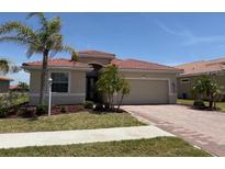 Charming single-story home boasts a well-manicured lawn and a brick-paved driveway leading to the garage at 7360 Talon Bay Dr, North Port, FL 34287