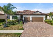 Charming one-story home featuring a terracotta roof, paved driveway, and meticulously landscaped front yard at 14309 Carolina Sky Pl, Lakewood Ranch, FL 34211