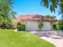 Charming home featuring a terracotta roof, two-car garage, well-manicured lawn, and lush landscaping at 1720 Kestral Park S Way # 49, Sarasota, FL 34231
