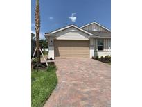 A charming home with a brick drive, tan garage door, and well maintained landscaping at 240 Ibiza Loop, Venice, FL 34292