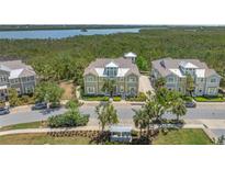 Beautiful townhouse with neutral tones, lush landscaping, and a view of the water and trees in the background at 241 Sapphire Lake Dr # 201, Bradenton, FL 34209