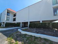 Bright condo building with stucco exterior, red roof, and well maintained landscaping in sunny weather at 3805 E Bay Dr # 302, Holmes Beach, FL 34217
