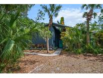 Charming home exterior features a unique design with lush landscaping and a welcoming blue front door at 5282 Box Turtle Cir, Sarasota, FL 34232