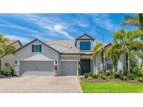 Beautiful single-Gathering home featuring a three-car garage, stone accents, and lush landscaping at 801 Seascape Pl, Sarasota, FL 34240